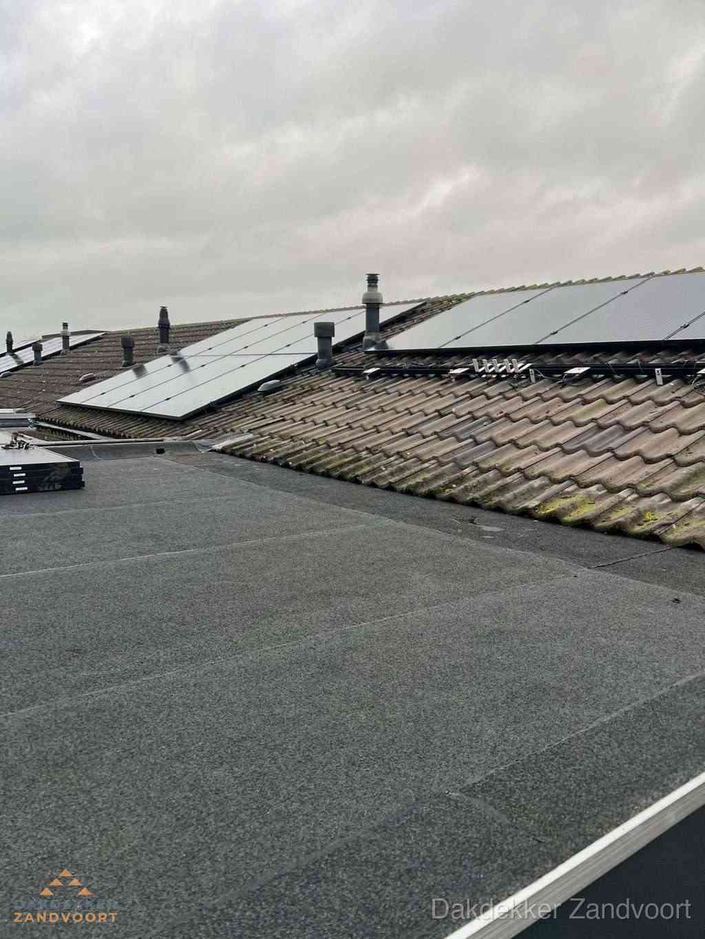 Plat dak inspectie met bitumen bedekking naast schuin pannendak in Zandvoort