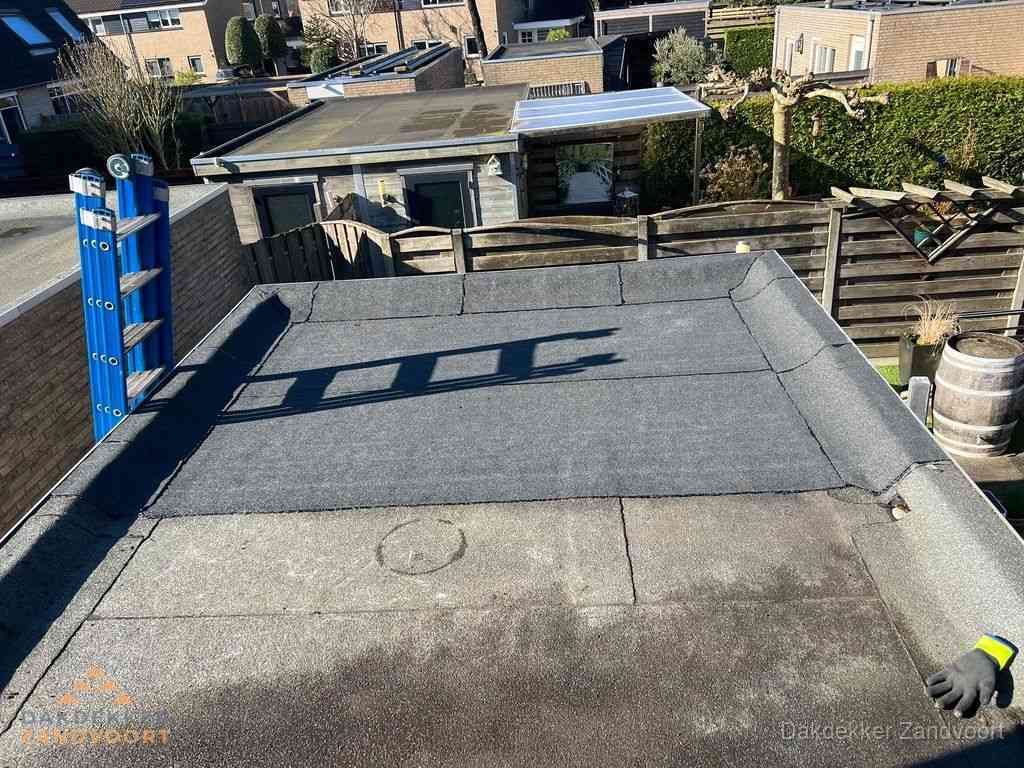 Dakdekker legt onderlaag op plat dak met houten constructie in Zandvoort