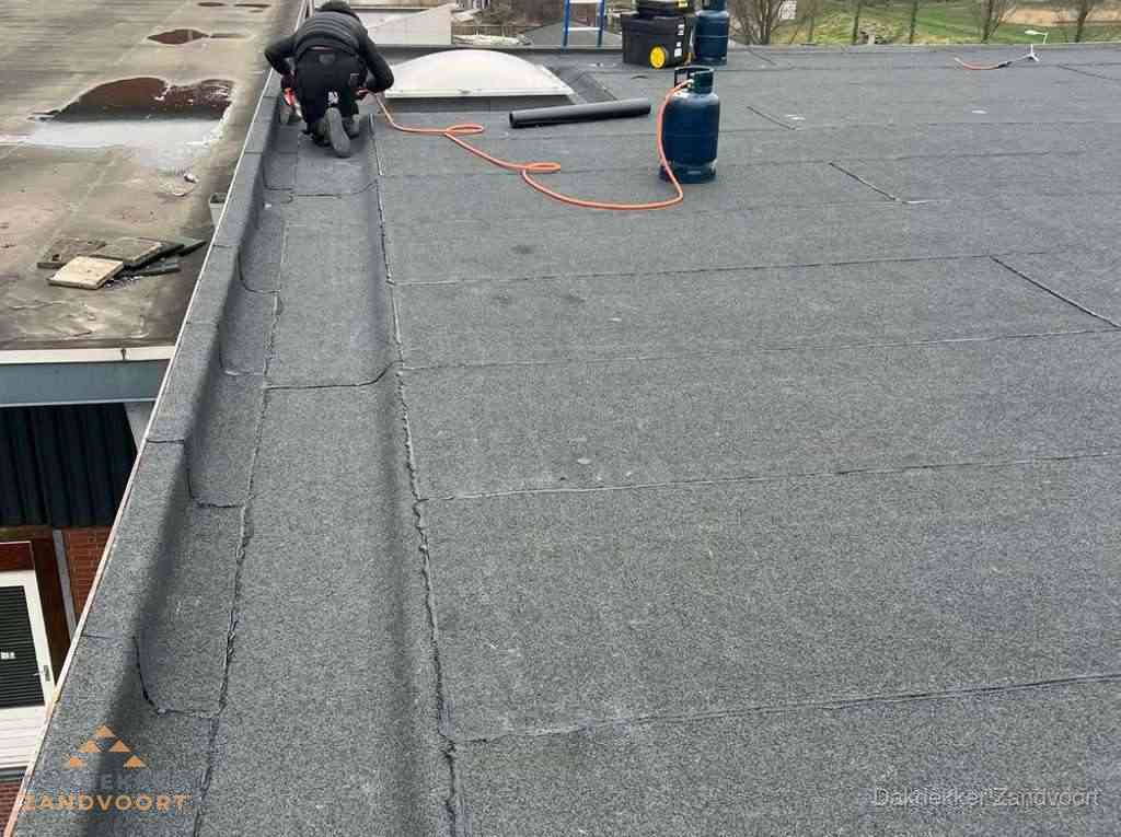 Dakdekker repareert bitumen dakbedekking op groot plat dak in Zandvoort