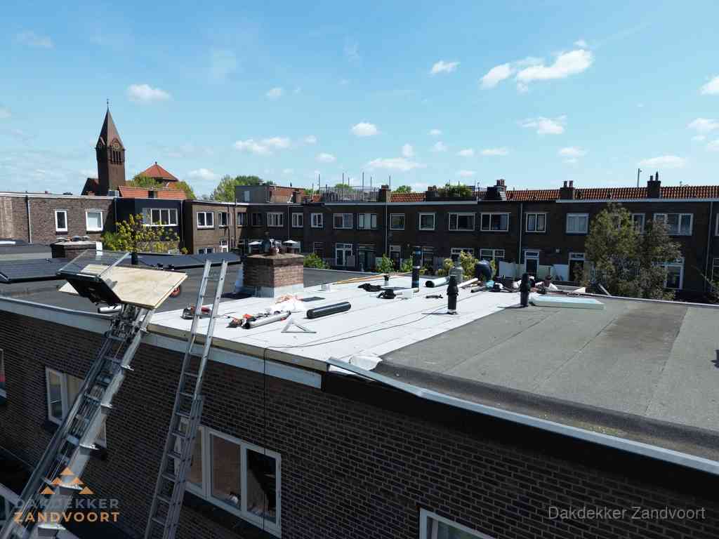 Dakdekkers aan het werk op plat dak in Zandvoort