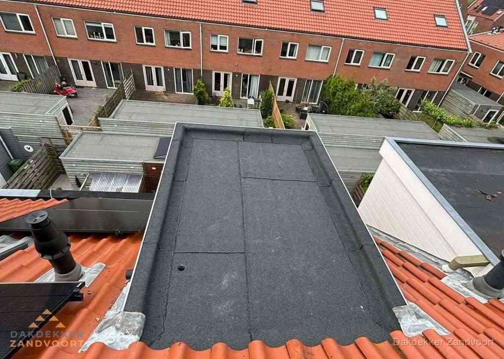 Plat dak met bitumen bedekking naast dakkapel in Zandvoort